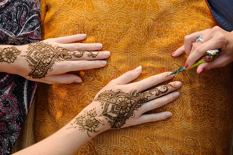 Applying henna tattoo on women hands - user20177777 magnific.com HealthServ